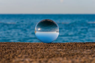 Glass transparent ball on sea background and grainy surface. Water clipart