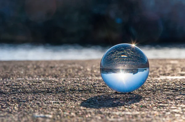 Glass transparent ball on dark background and grainy surface. — Stock Photo, Image