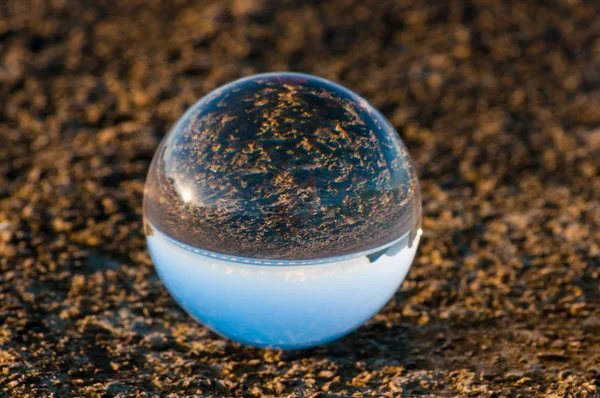 Glass transparent ball on dark background and grainy surface. — Stock Photo, Image