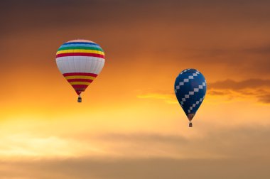 İki sıcak hava balonları günbatımı gökyüzü arka plan üzerinde uçuş. Renkli Balon Festivali. Açık, renkli