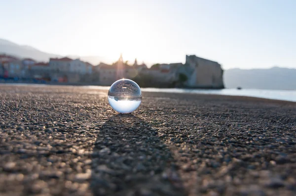 Стеклянный прозрачный шар на морском фоне и зернистой поверхности. Вода — стоковое фото