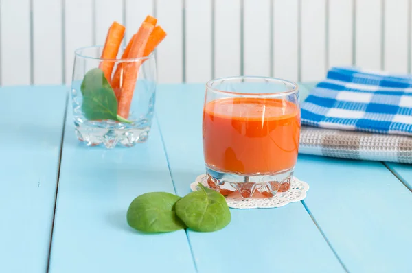 Jugo de zanahoria casero saludable en vaso y zanahorias frescas sobre fondo de madera clara . — Foto de Stock