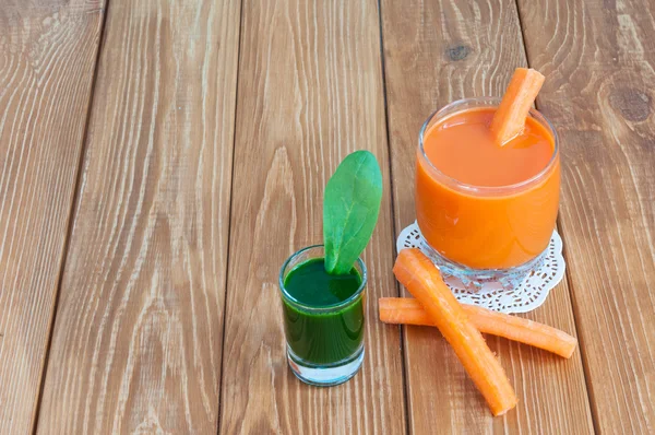 Hälsosam hemlagad morotsjuice i glas och färsk morot, spenat på ljus trä bakgrund. — Stockfoto