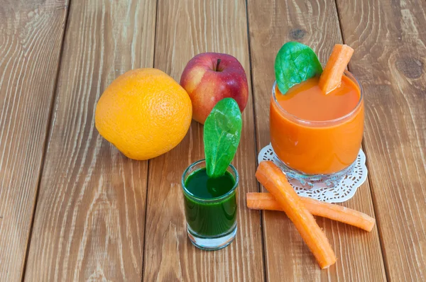 Jugo de zanahoria casero saludable en vidrio y zanahoria fresca, espinacas sobre fondo de madera clara . —  Fotos de Stock