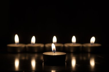 One candle and group of candles on old wooden background clipart