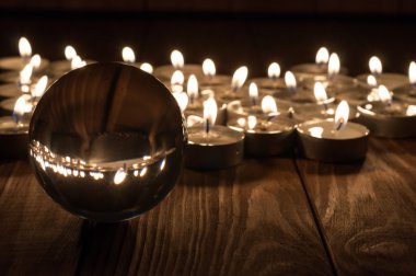 Cam şeffaf topun ve eski ahşap arka plan üzerinde yanan mumlar