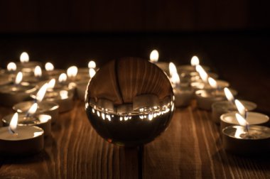 Cam şeffaf topun ve eski ahşap arka plan üzerinde yanan mumlar