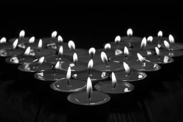 Black and white candles in the shape of heart on old wooden background — Stock Photo, Image