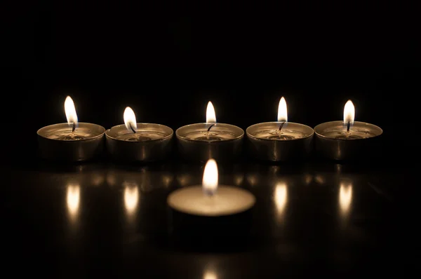 Jedna svíčka a skupina svíček na staré dřevěné pozadí — Stock fotografie