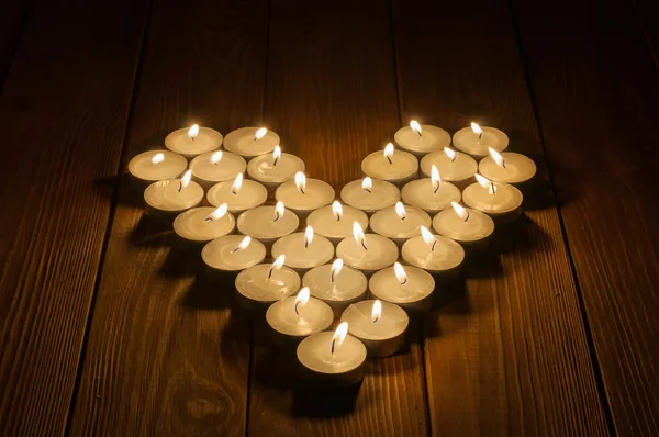 Velas en forma de corazón sobre fondo de madera viejo —  Fotos de Stock