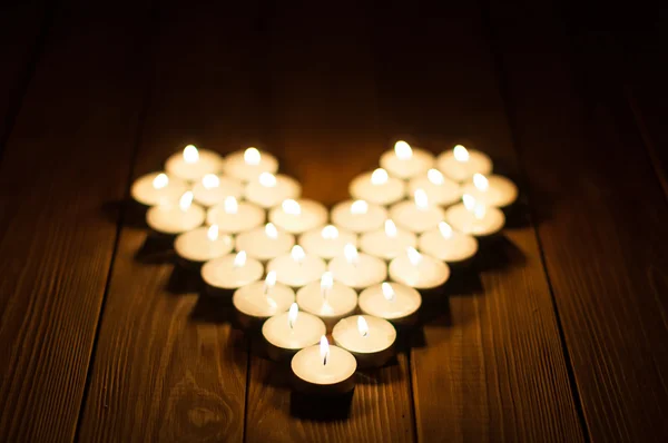 Candles in the shape of heart on old wooden background — Stock Photo, Image