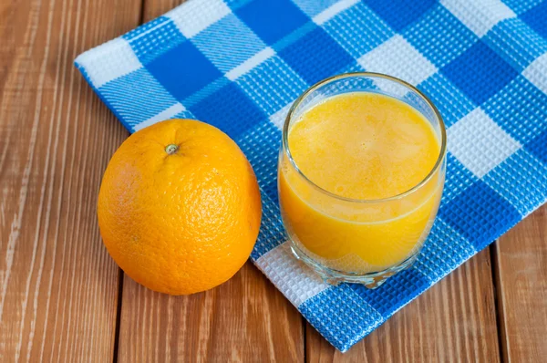 Jugo de naranja casero saludable en vidrio y fruta fresca sobre toalla a cuadros azul, fondo de madera . — Foto de Stock