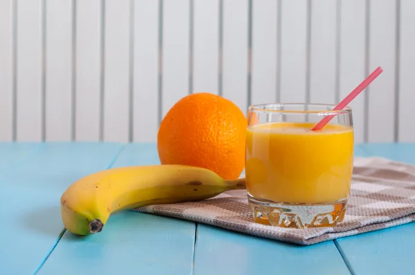 Zumo cítrico fresco con plátano y naranja sobre fondo de madera blanca —  Fotos de Stock