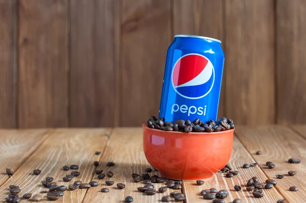 Kiev, Ucrania, abril de 2015. Can Pepsi cola en un tazón de café de pie sobre fondo de madera oscura con espacio vacío. Refresco carbonatado producido y fabricado por PepsiCo. Creado, desarrollado —  Fotos de Stock