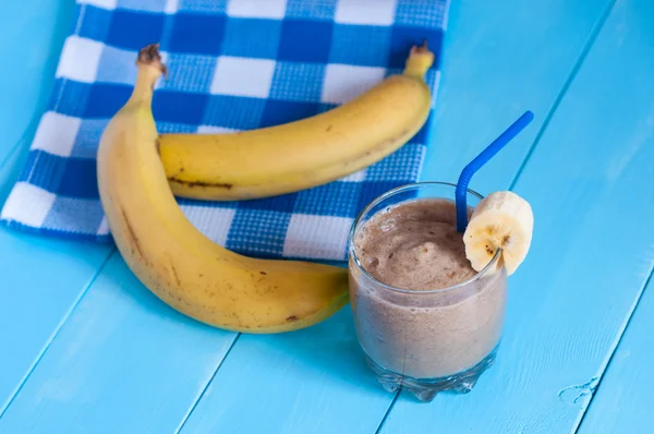 Batido de plátano de chocolate casero saludable en vidrio y plátanos frescos sobre fondo de madera clara . —  Fotos de Stock