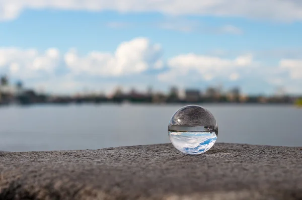 Glazen transparant bal op rivier achtergrond en korrelig oppervlak. Met lege ruimte — Stockfoto