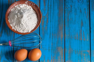Pişirme kek içinde kırsal kitchen - hamur tarifi Malzemeler yumurta, un ve fırçalamak yukarıdan vintage ahşap masa üzerinde. Serbest metin alanı olan rustik arka plan.