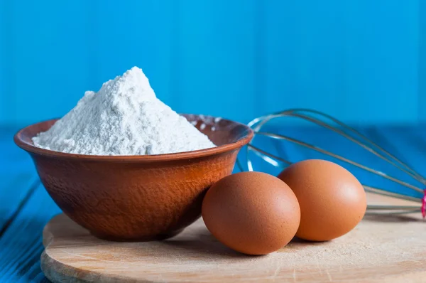 Baking cake in rural kitchen - dough recipe ingredients eggs, bowl with flour and whisk, screen on vintage wood table from above — Stock Photo, Image