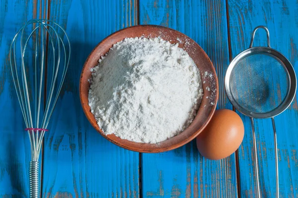 Baking cake in rural kitchen - dough recipe ingredients eggs, flour and whisk, screen on vintage wood table from above — Stock Photo, Image