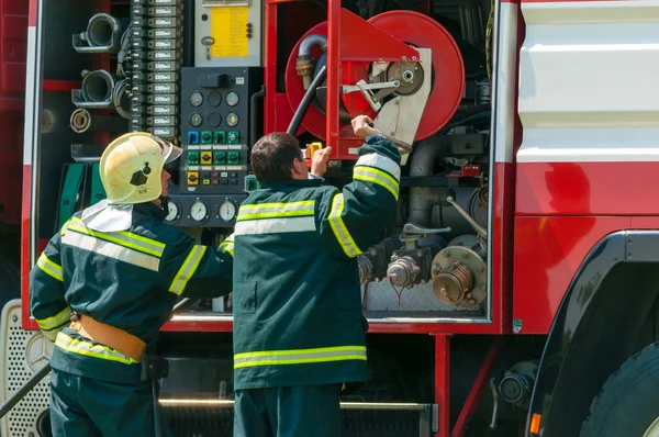 BORYSPIL, UCRANIA - 20 DE MAYO DE 2015: Bombero levantó la manguera roja después de entrenar apagar el fuego en el Aeropuerto Internacional de Boryspil, Kiev, Ucrania . —  Fotos de Stock