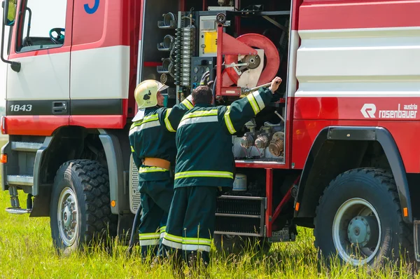 BORYSPIL, UCRAINA - 20 MAGGIO 2015: Il pompiere ha sollevato il tubo rosso dopo l'allenamento ha posticipato l'incendio all'aeroporto internazionale di Boryspil, Kiev, Ucraina . — Foto Stock