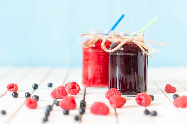 Rustic Mason Jars with raspberry jam and bog bilberry marmalade, fresh berries on white wooden background.  Selective focus — Stockfoto