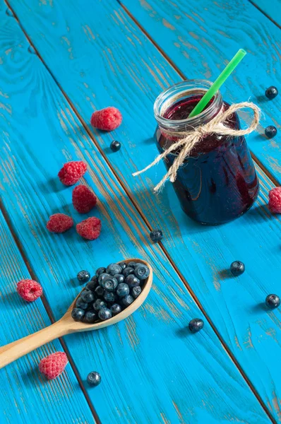 Mason jar with berries jam or marmalade and fresh raspberry, blueberry on a rustic wooden table. Cooking background, unique perspective — Stock Photo, Image