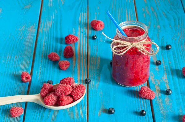 Mason jar with raspberry jam or marmalade and fresh raspberries, blueberries on a rustic wooden table. Cooking background — Stockfoto