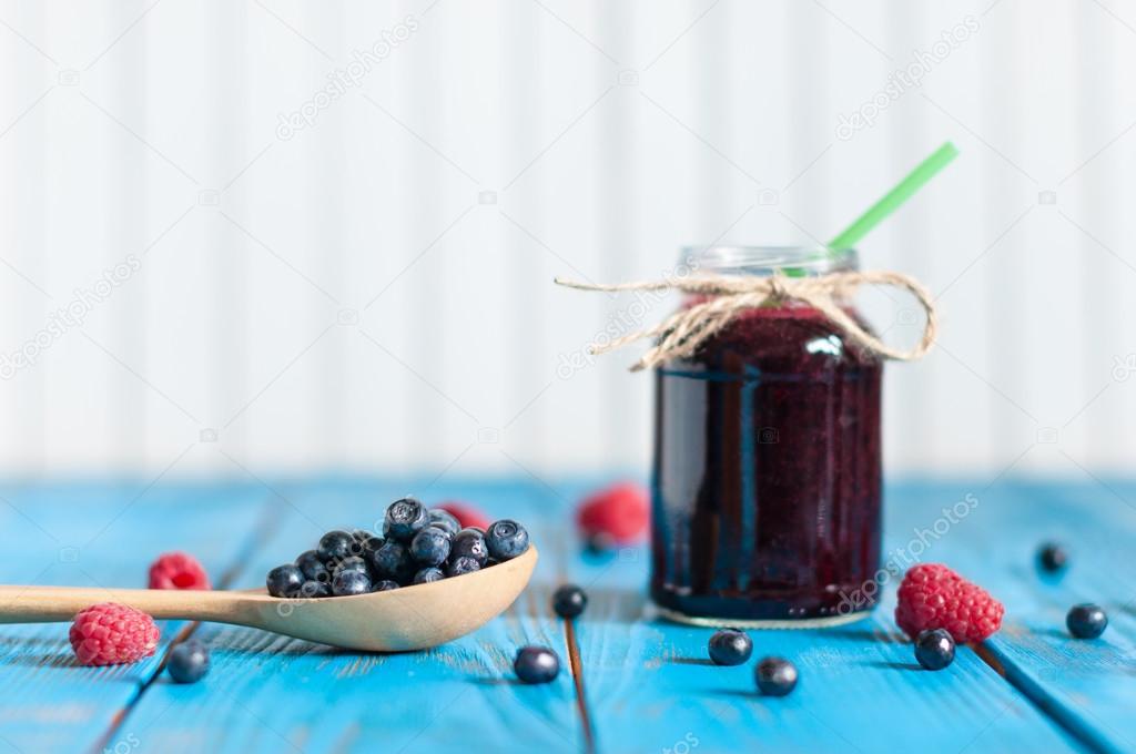 Blueberry smoothie or homemade jam in mason jar with fresh berries on light rural background. Selective focus