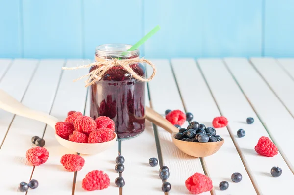 Bramen jam in mason kruik en verse frambozen, bosbessen op een houten tafel. Macro opname, selectieve aandacht — Stockfoto