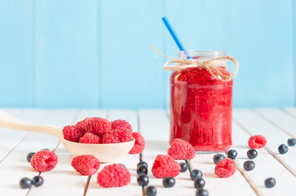 Raspberries jam in mason jar and fresh berries on rural wooden table. — Stock Photo, Image