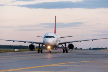 Perspective view of jet airliner at taxiway. Evening scene with travel background