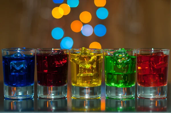 Five glasses with berry liqueur on the bar counter at a nightclub, magic light bokeh — Stock Photo, Image
