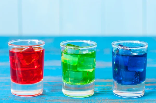 Three kinds of alcoholic drinks in shot glasses on bar counter and light background — Stock Photo, Image