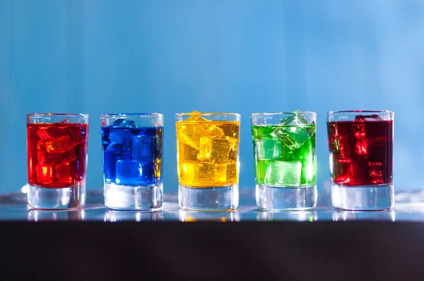 Bright alcohol drinks or berries cocktail in different colours, glasses tumbler on wooden backfround — Stock Photo, Image