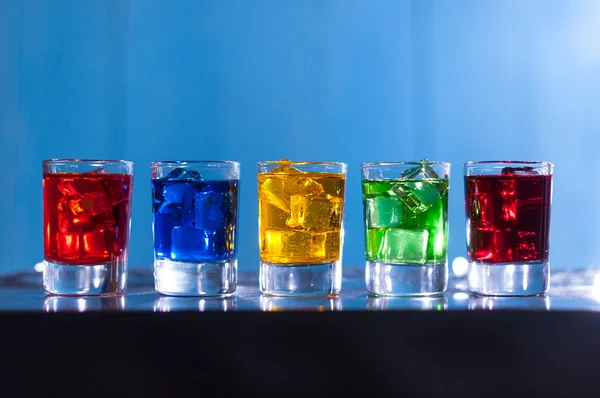 Five glasses with alcohol cocktail on the bar at nightclub, blue background — Stock Photo, Image