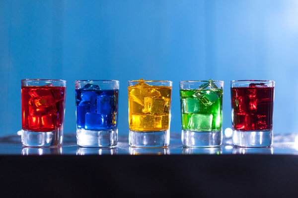 Пять стаканов с алкогольным коктейлем в баре в ночном клубе, синий фон
