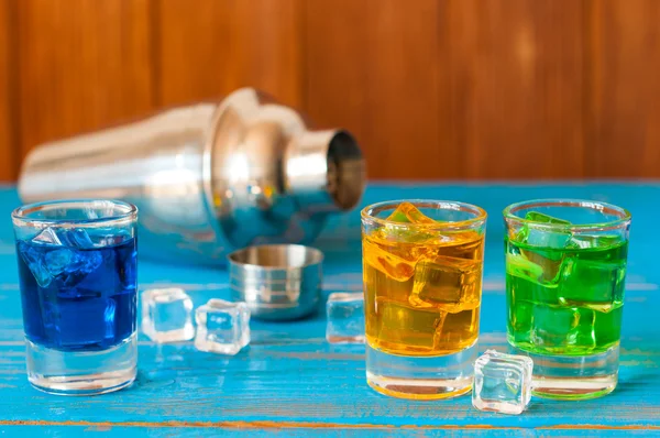파랑, 녹색, 빨간색 알코올 이나 알코올 없는 칵테일 얼음 조각 및 셰이 커 바에 카운터, 나무 배경. — 스톡 사진