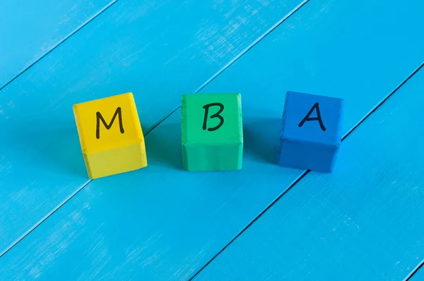 MBA o Master of Business Administration segno su cubi colorati per bambini in legno, blocchi e sfondo in legno blu — Foto Stock