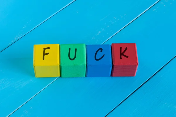 Fuck - word on childrens colourful cubes or blocks. Colourful wooden background — Stockfoto