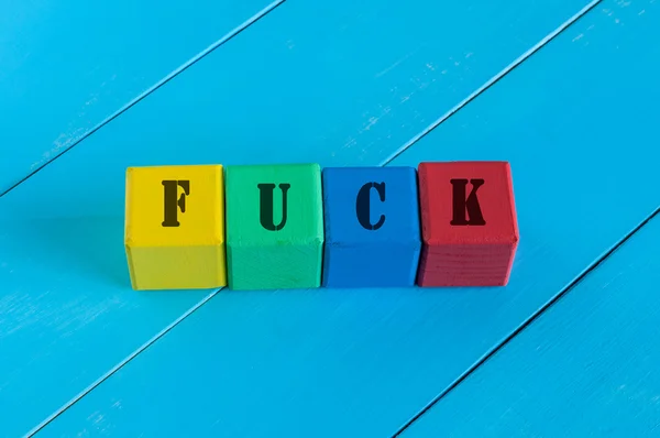 Fuck - word on childrens colourful cubes or blocks. Colourful wooden background — Stockfoto