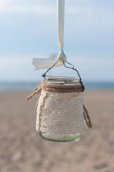 Jar with lace for candle on the beach and sea background, vintage decor — Stock Photo, Image
