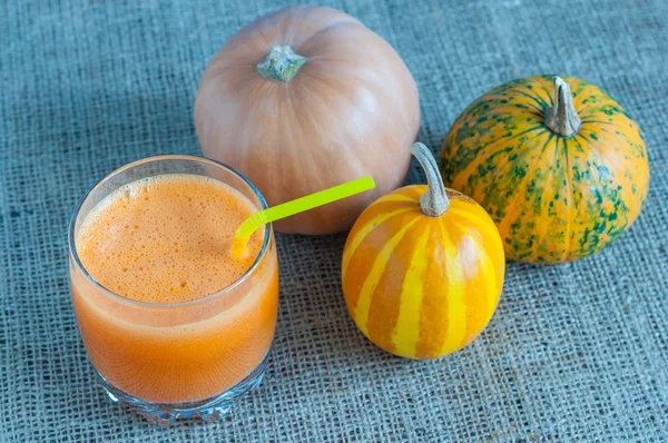 Healthy Pumpkin Spice Smoothie and three different pumpkins on sackcloth surface — Stock Photo, Image