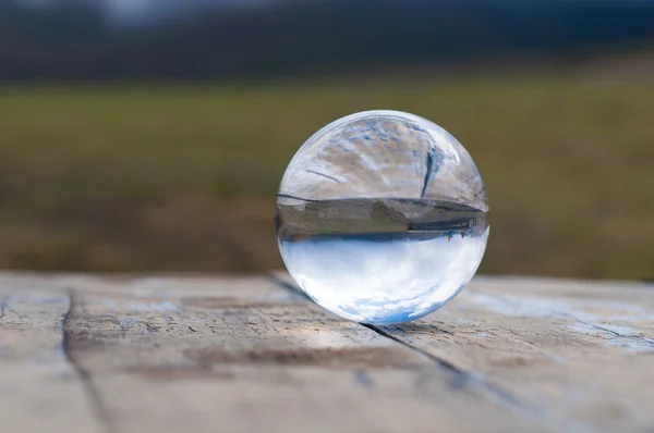 Bola transparente de vidrio sobre fondo verde oscuro y superficie de madera. Foco suave. Con espacio vacío para texto —  Fotos de Stock