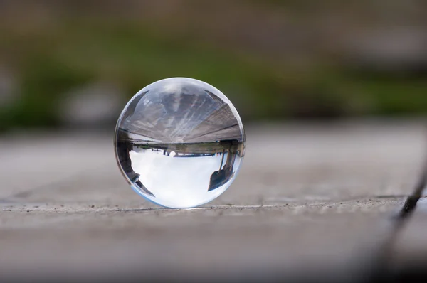 Üveg átlátszó labda sötétzöld háttér és fa felülettel. Lágy fókusz. A üres hely a szöveg — Stock Fotó