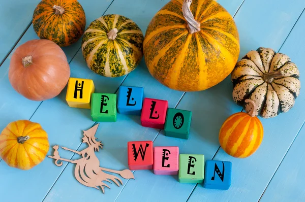 Word Helloween op childs toy kubussen en pompoenen met heks silhouet op houten plattelandsachtergrond. — Stockfoto