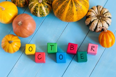 October wooden blocks with many-coloured pumpkins and decor against an old wood background