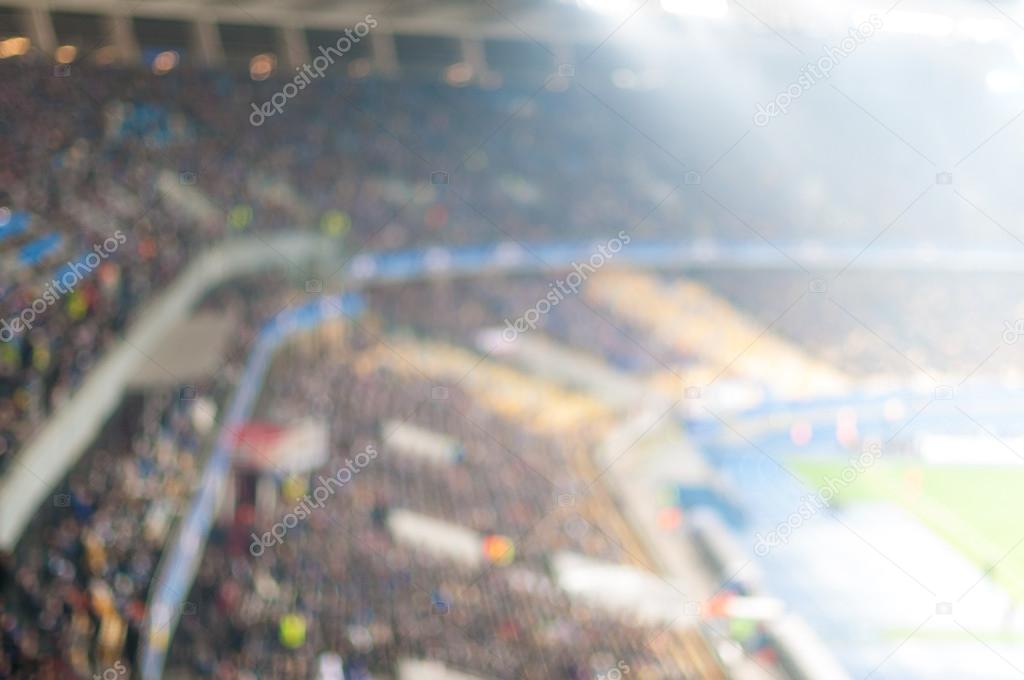 Blurred crowd of spectators on a stadium with football match.