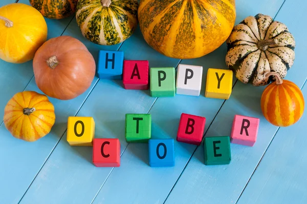 Fröhlicher Oktober Holzklötze mit vielfarbigen Kürbissen und Dekor vor altem Holzhintergrund — Stockfoto