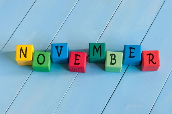 Word November On childs toy cubes on wooden rural  background. — Stock Photo, Image